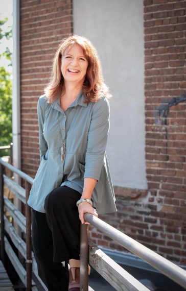 Dr. Ross outside sitting on a railing, smiling.